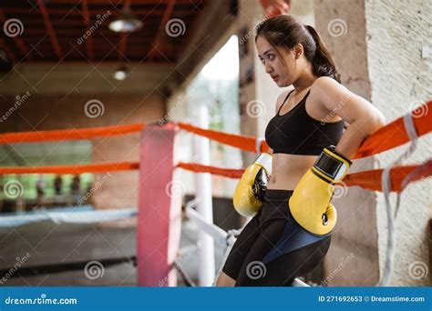 A Female Boxer With Yellow Boxing Gloves Leaning On The Ropes Stock