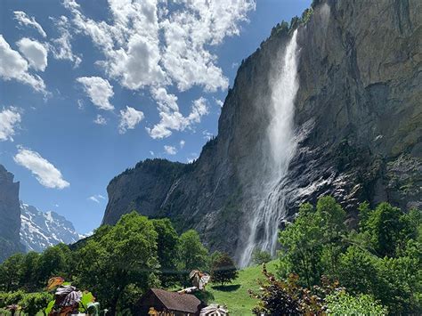 A Group Of People Standing In Front Of A Waterfall On A Sunny Day With