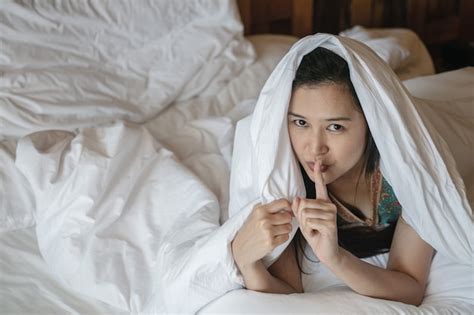 premium photo closeup asian woman lie on bed under blanket and make a gesture to tell the