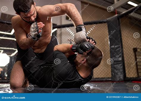 Shirtless Strong Mma Fighter In Boxing Gloves Sitting Above Opponent While Sportsman Lying On