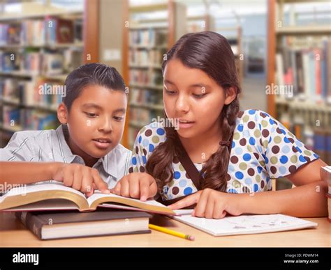 Hispanic Boy And Girl Having Fun Studying Together In The Library Stock