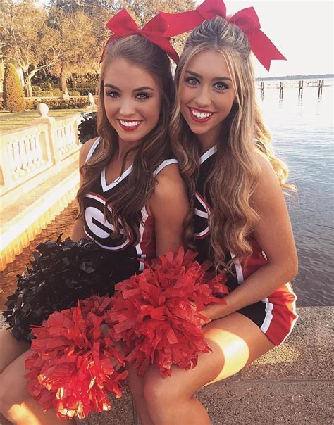 Two Cheerleaders Posing For The Camera With Their Pom Poms