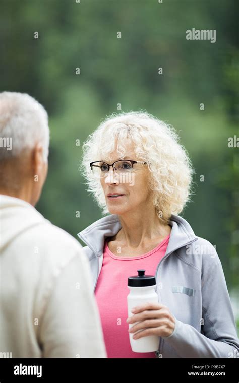 Blonde Wavy Haired Woman With Bottle Of Water Talking To Her Husband