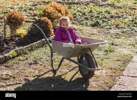 Happy Little Girl Sitting In Wheelbarrow Stock Photo Alamy