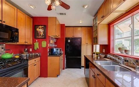 Bright red is an ideal color to use with your brown acrylic kitchen cabinets. red walls, oak cabinets, black appliances | Red kitchen ...