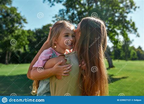 Loving Mother Cuddling With Her Cute Little Daughter Holding Her While Relaxing Together In