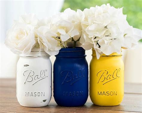 Three Painted Mason Jars With Flowers In Them