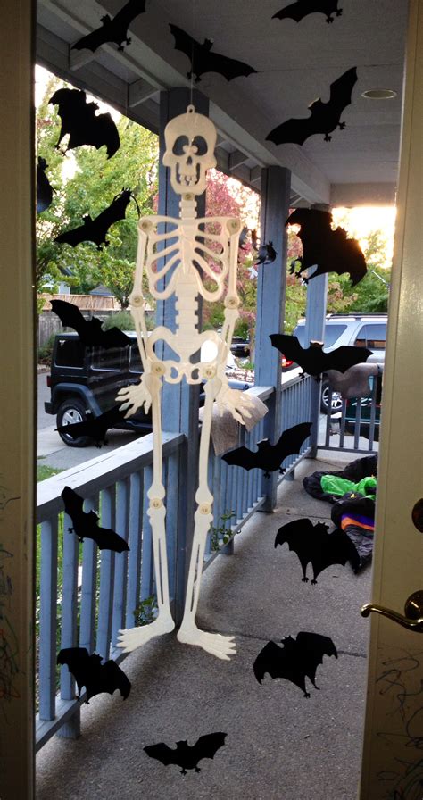 A Porch Decorated For Halloween With Skeletons And Bats