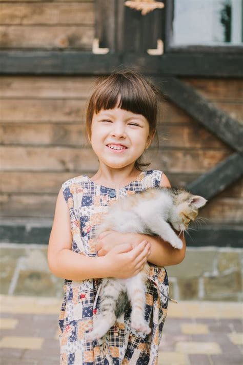 Cheerful Little Girl Holding A Frightened Cat In Hands Stock Photo