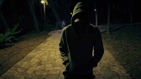 Suspicious Hooded Figure Walks In A Dark Park At Royalty Free Video