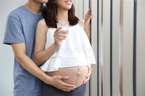 Full Length Shot Of Portrait Of Asian Young Pregnant Belly Wife And Asian Husband Holding