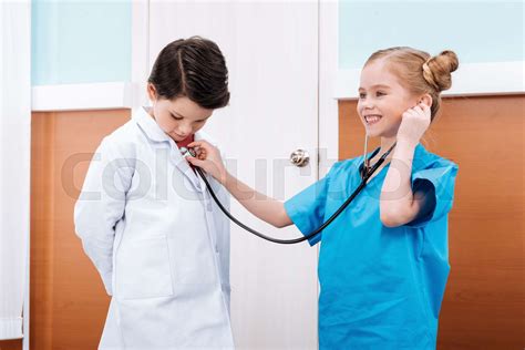 Smiling Girl Nurse With Stethoscope Listening Heartbeat Of Boy Doctor