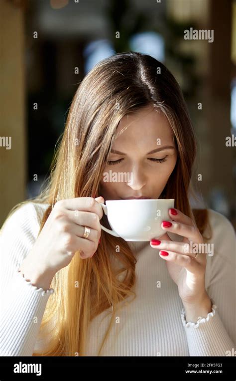 Beautiful Attractive Business Woman In A White Blouse Drinks Cofee In