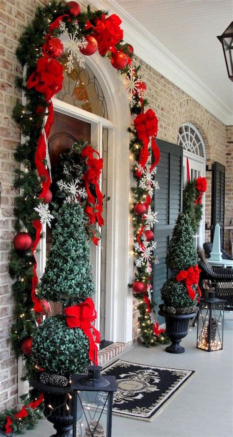 The Front Porch Decorated For Christmas With Red And Green Decorations