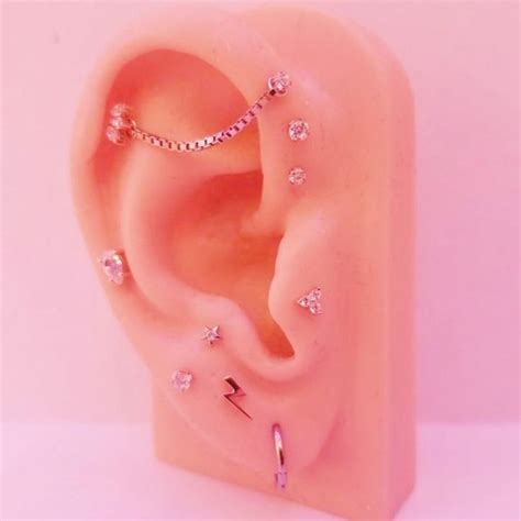 A Fake Ear With Some Piercings Attached To Its Side On A Pink Background