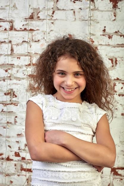 Premium Photo Young Joyful Girl Smiling Shyly Over A Brick Wall Crossed Her Arms Relaxed