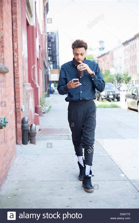 Young Man Walking Down Street With Cellphone And Drink