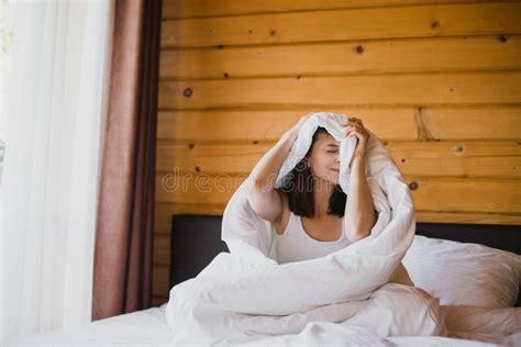 Young Woman Having Good Morning In Bed In Cozy Wooden House Stock