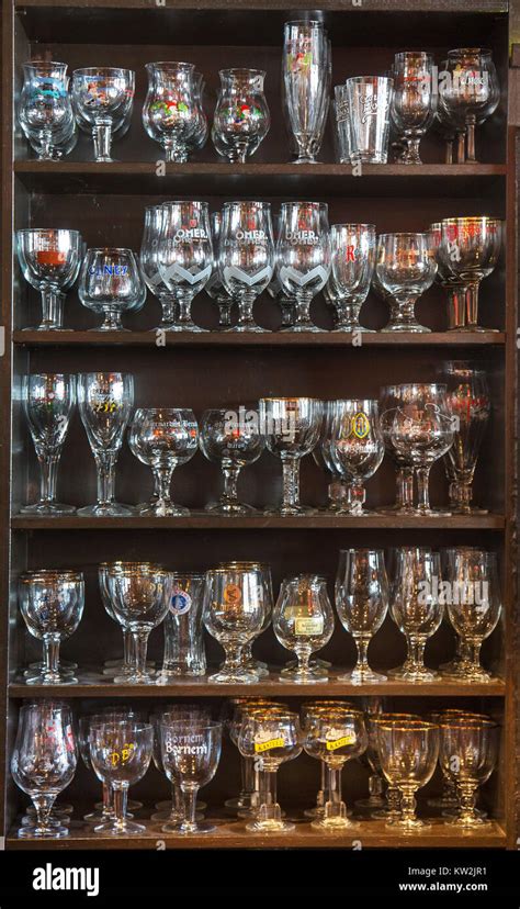 Assortment Of Beer Glasses Of Different Belgian Beers Displayed On Wooden Shelves In Café