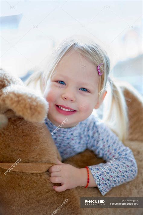 Smiling Girl Holding Teddy Bear — At Home Pigtail Stock Photo