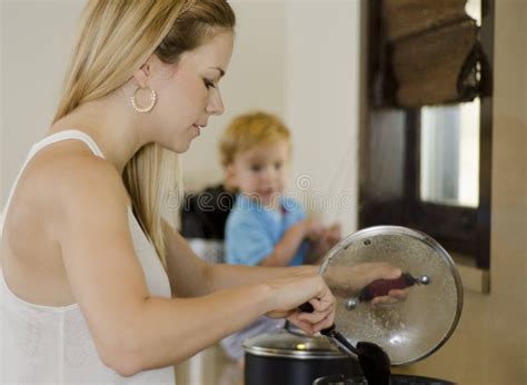 Mamá Que Cocina Mientras Que Relojes Del Hijo Imagen De Archivo