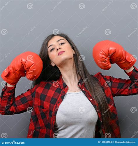 Portrait Of Young Woman Posing With Boxing Gloves Against Gray