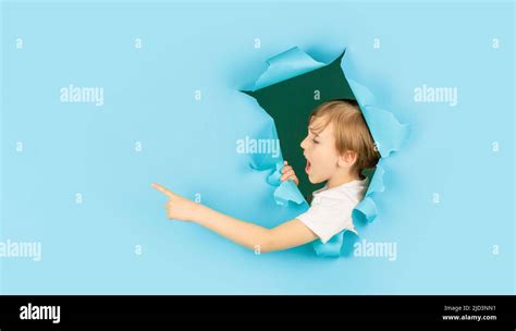 Boy In Blue Paper Hole Pointing With Finger Aside Screams Boy Looking