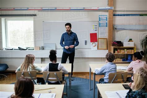 Confident Teacher Explaining Students In Classroom At School Stock