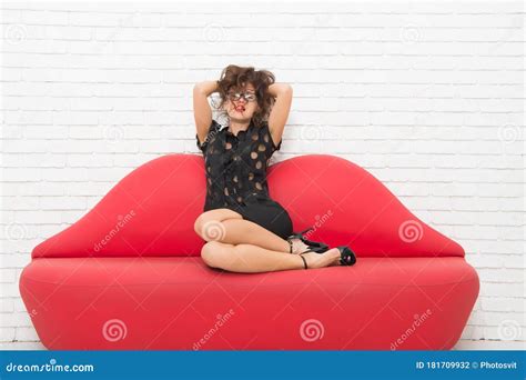 Relaxed Girl Sitting On Red Sofa Model On Leather Couch Beautiful Luxurious Woman Seducing You