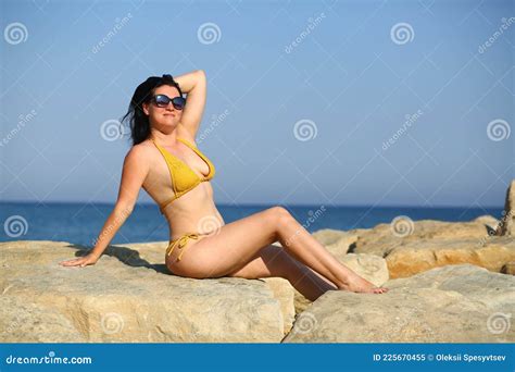 Caucasian Woman In Thirties Sunbathing On The Rocks On The Seashore