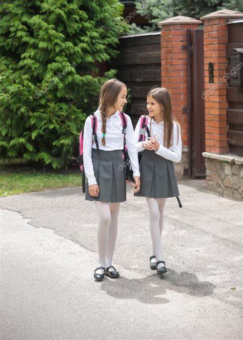 Cute Girls In Uniform Walking To School And Chatting Stock Photo By