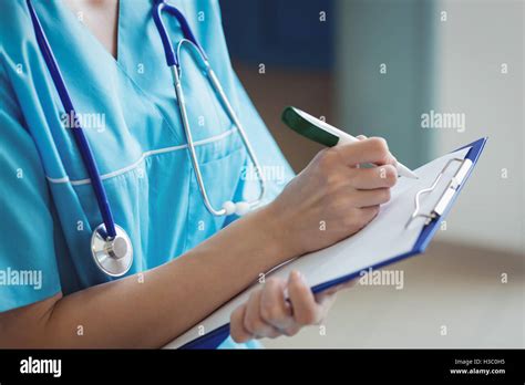 Mid Section Of Nurse Writing On Clipboard Stock Photo Alamy