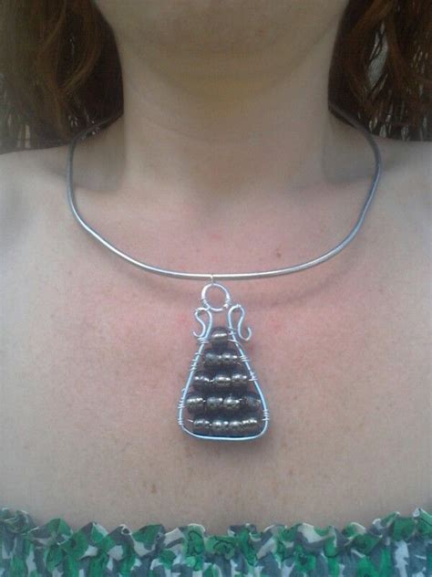 A Woman Wearing A Silver Necklace With A Pendant On It S Neck And An Object In The Middle