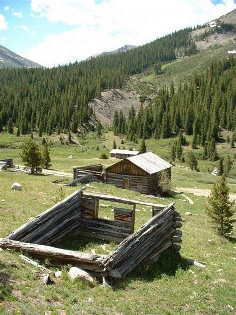An Old Outhouse In The Middle Of A Mountain Valley With Pine Trees And