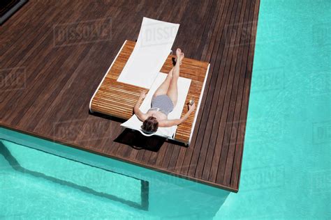 Woman Sunbathing At Poolside Stock Photo Dissolve