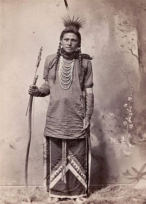 An Old Black And White Photo Of A Native American Man With Two Spears