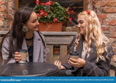 Two Girls Are Drinking Coffee On The Street And Talking Stock Image