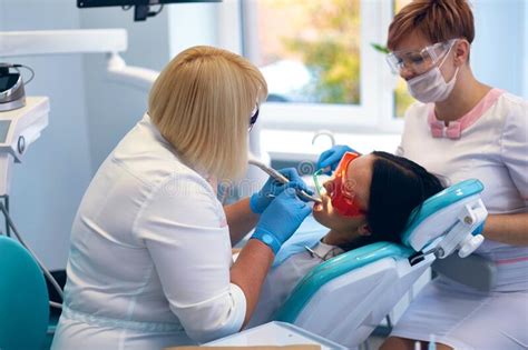 Doctor Dentist Treats Teeth Of A Beautiful Young Girl Patient Stock