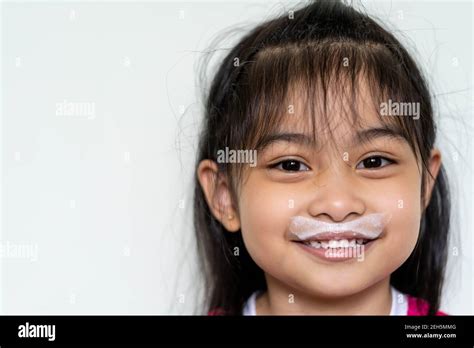 close up fun portrait of cute asian girl showing white milk mustache isolated against light