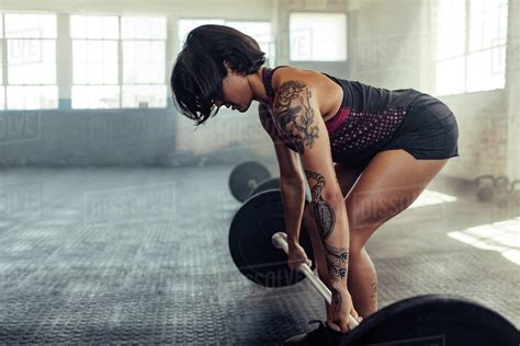 Focused Young Woman Weightlifting At Gym Tattooed Female Practicing Deadlift With Barbell