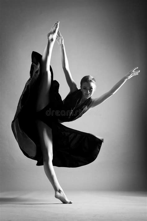 A Beautiful Athletic Girl In A Black Dress Is Dancing In The Jump