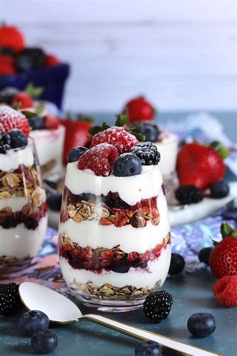 Layered Cheesecake Parfait With Berries And Muesli In A Wine Glass On A