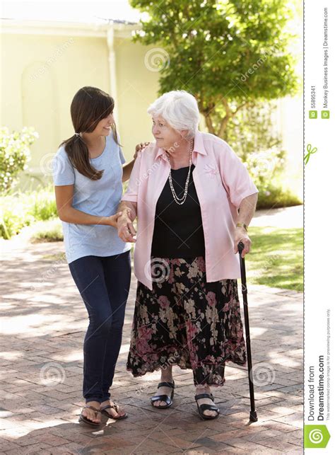 Teenage Granddaughter Helping Grandmother Out On Walk Stock Image