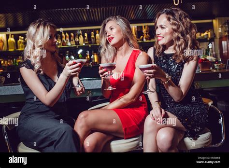 Beautiful Women Are Sitting On The Bar And Drinking Cocktails Stock