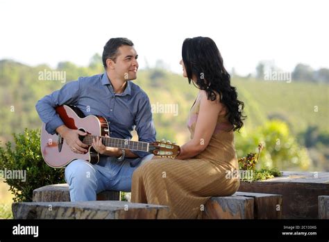 Portrait Of Beautiful Young Wedding Couple Posing In Outdoor Photoshoot Playing Guitar Stock