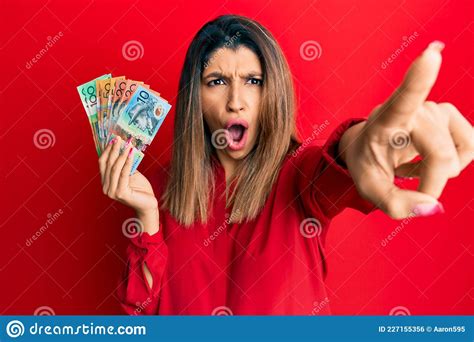 Beautiful Brunette Woman Holding Australian Dollars Pointing With Finger Surprised Ahead Open