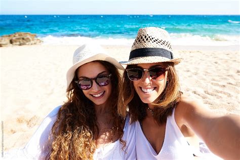 View Two Friends In Sunglasses And Hats Smiling At Camera By Stocksy