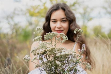 Premium Photo Portrait Of A Brunette Girl On Nature White Dress And A Bouquet Of Wildflowers