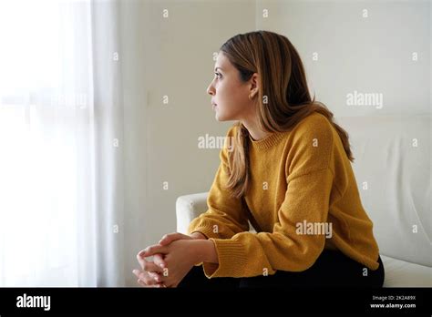 Melancholic Sad Woman Looking Through The Window At Home Stock Photo