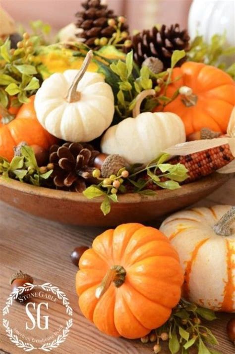 A Wooden Bowl Filled With Pumpkins And Greenery On Top Of A Wood Table